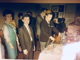 YoungPa cutting a challah at a table, with family members looking on